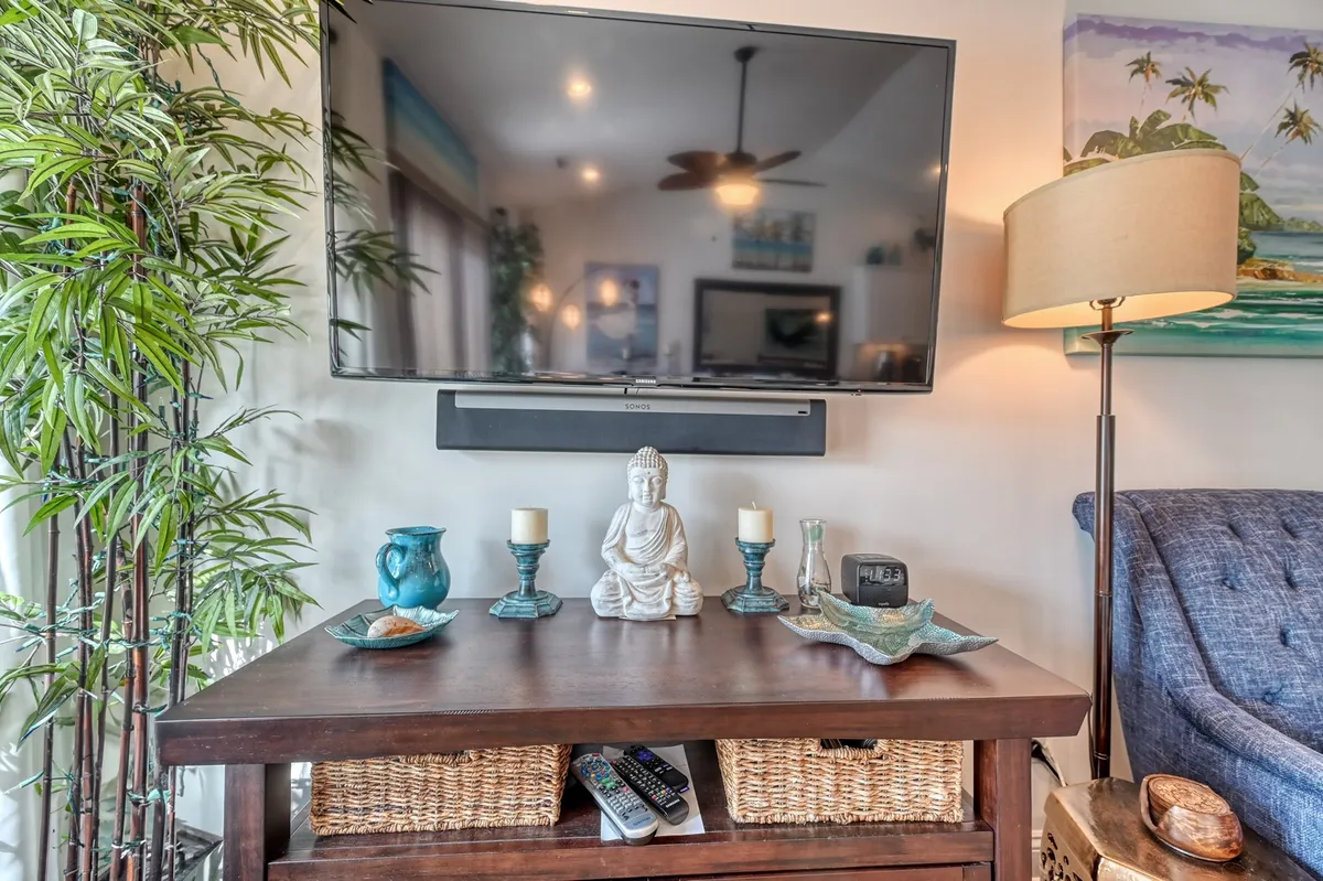A cozy living area featuring a Buddha statue, decorative items, a lush plant, a lamp, and a TV, creating an inviting and tranquil space for relaxation and mindful reflection after an active day outdoors.