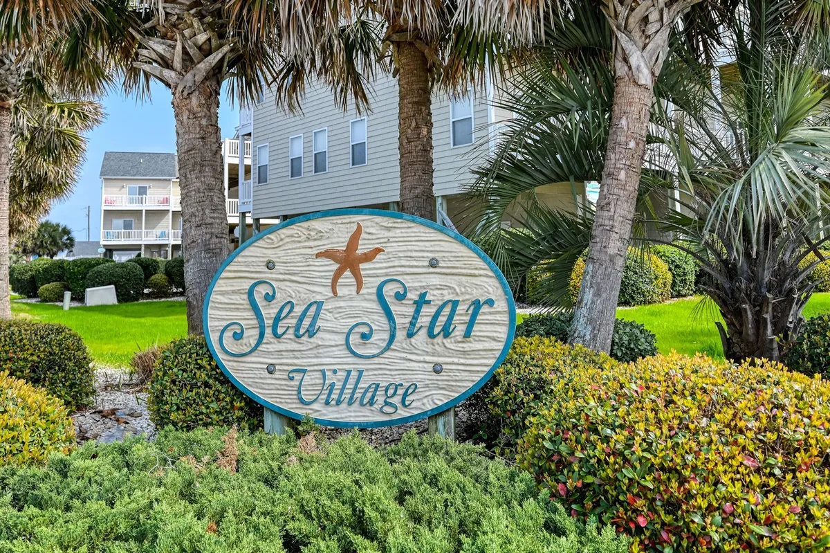 An exterior shot featuring the inviting Sea Star Village sign, surrounded by lush greenery and palm trees. The tranquil setting hints at local exploration and a sense of arrival to a special coastal community.