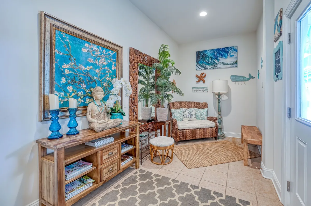 This interior nook features a woven chair, large blue cherry blossom artwork, a Buddha statue, and tropical plants. The arrangement creates a welcoming, calm corner ideal for reading or quiet reflection, embodying the idea of hidden corners for personal retreat.